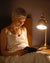 Femme qui lit un livre avec une veilleuse sur sa table de chevet