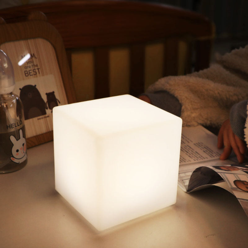Cube veilleuse allumé sur une table de chevet