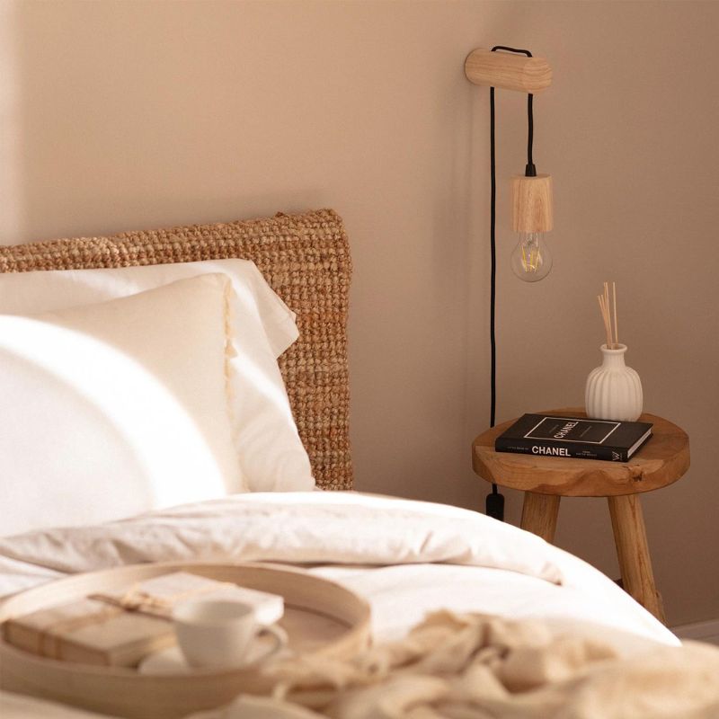 lampe de chevet suspendu bois torse allumée dans une chambre à coucher