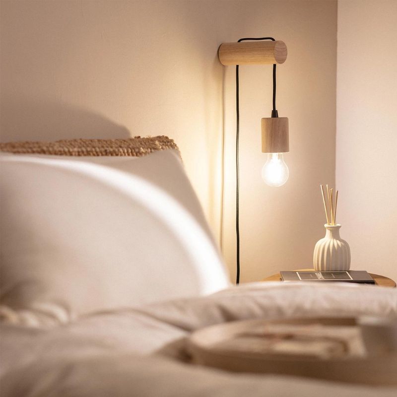 lampe de chevet suspendu bois torse allumée dans une chambre à coucher