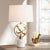 Lampe de chevet blanche éteinte design sur une table en bois à coté d'un livre et un vase