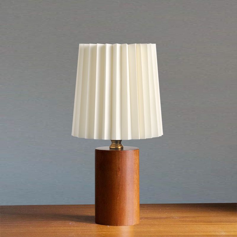 lampe de chevet design bois scandinave clair allumée sur un meuble noir